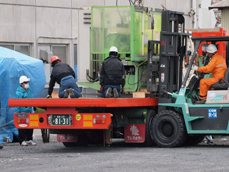 生産再開に向け機械を運び出す従業員